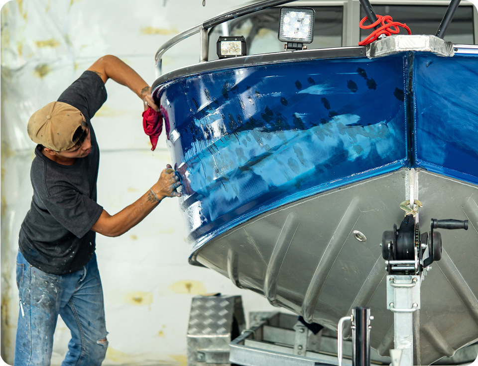 Man polishing a blue boat hull