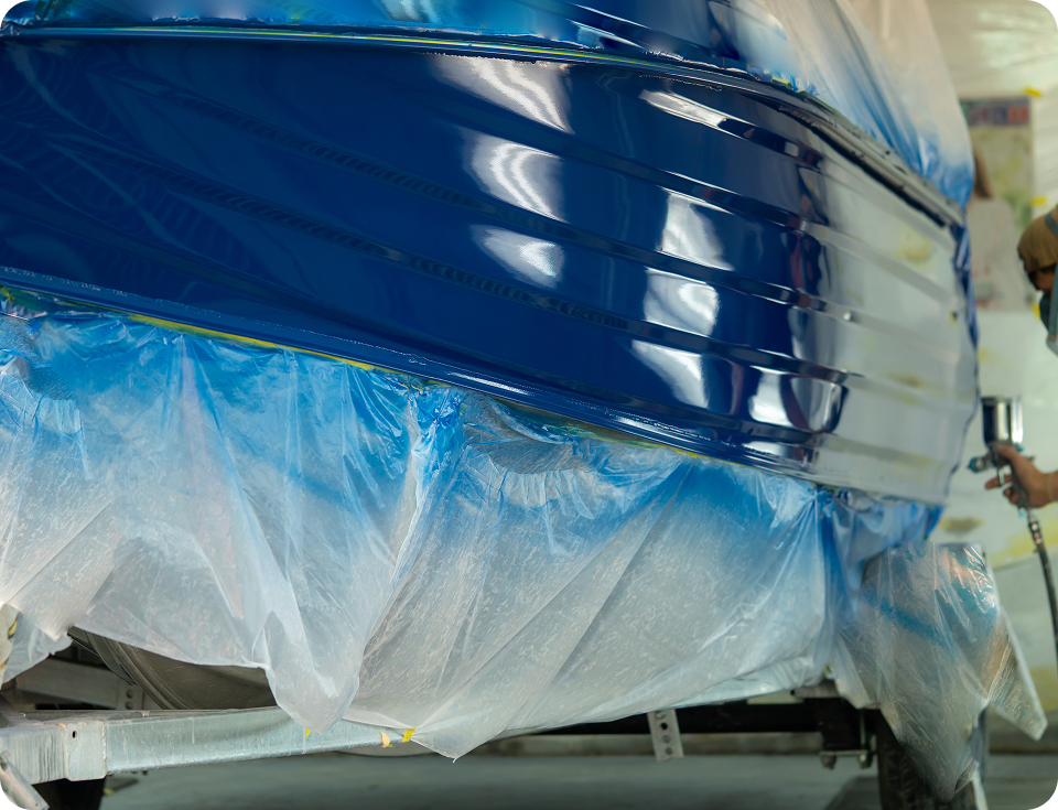 Worker spray painting a boat